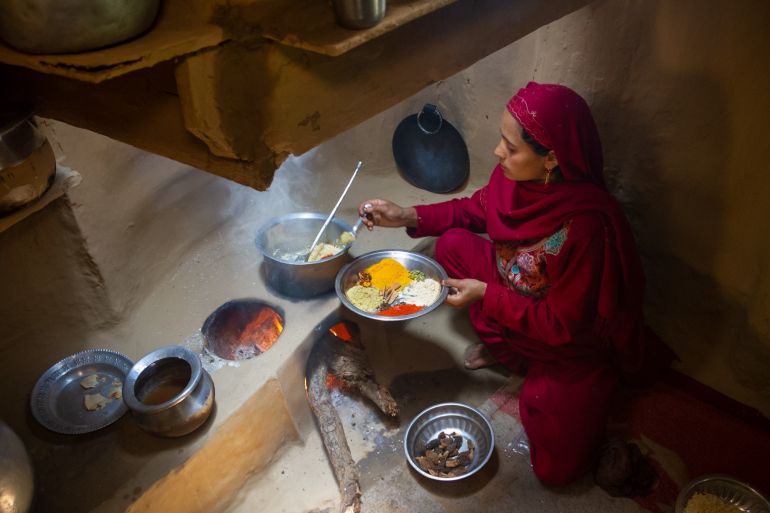 A view of Shaheena as she cookes the Gucchi Pulav, a plate of spices in her left hand as she adds spices to the pot with her right
