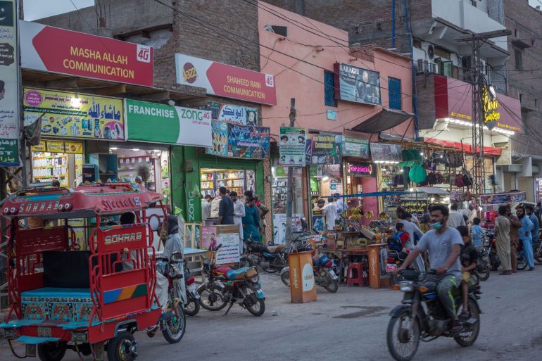 Traffic and pedestrians pass shops and market stalls illuminated by solar-powered bulbs in Jacobabad, Pakistan