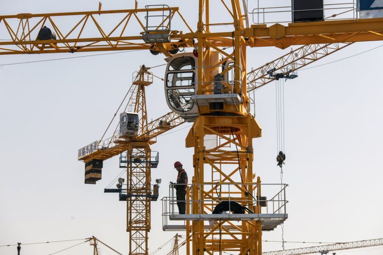A worker stands on a crane at the Sunac Resort project construction site in Zhejiang Province, China