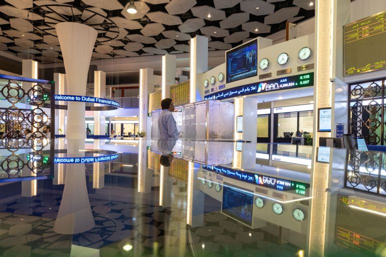 An investor watches a television news report at the Dubai Financial Market PJSC (DFM) in Dubai, United Arab Emirates