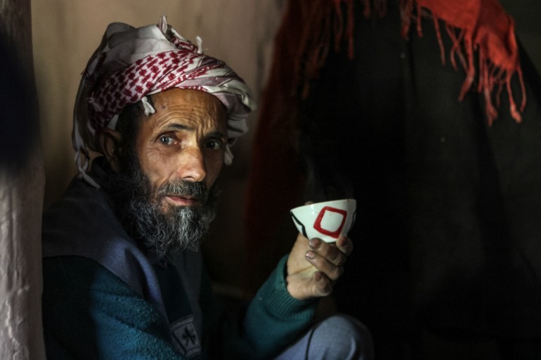 Abdul Karim looks to the right at the camera as he balances his teacup in his left hand