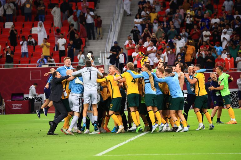 The Australian football team celebrates victory on the pitch.