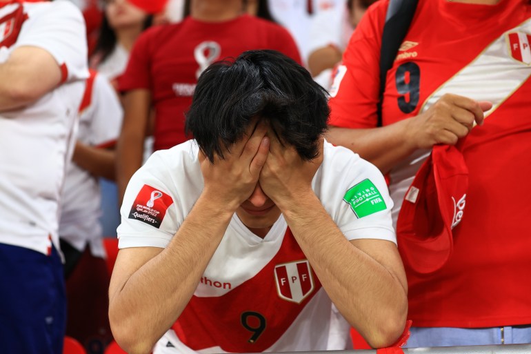 A dejected Peru fan holding his head in his hands.