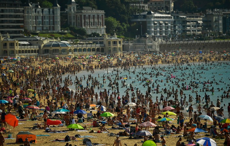 2018 年 8 月 3 日星期五，人们在西班牙北部巴斯克城市圣塞巴斯蒂安的拉孔查海滩上挤满了人。 