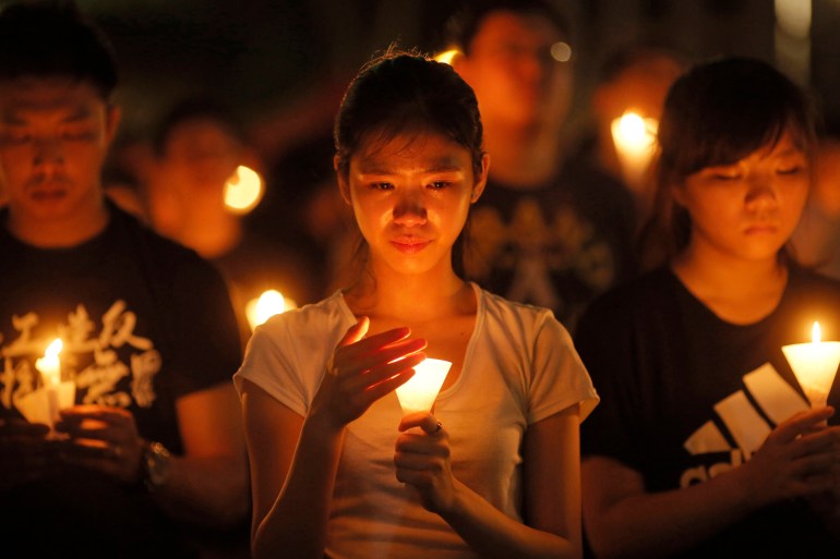 A woman holds a candle that illuminates her face during the Tiananmen Square vigil in 2015