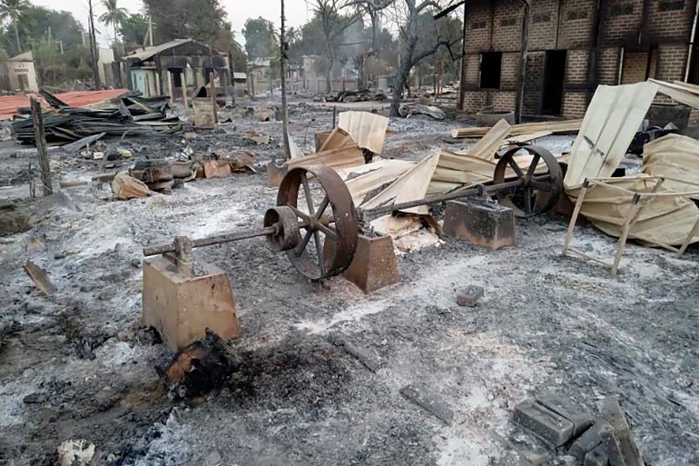 Обугленные дома лежат в кучах пепла в сожженной военными деревне в районе Сагайн.