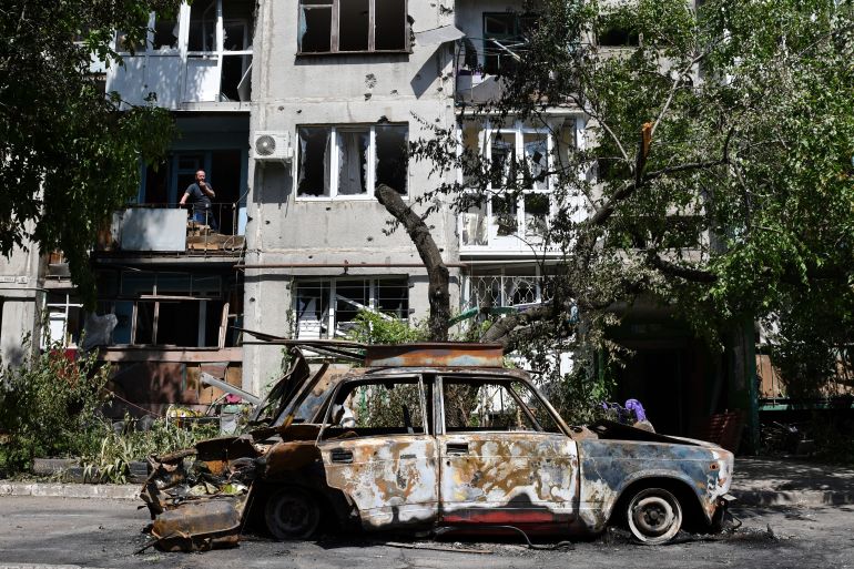 A destroyed car lies next to a damaged apartment building in Sloviansk, Ukraine.