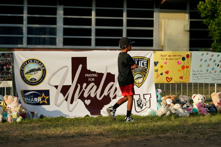 A boy walks along a memorial outside Robb Elementary School in Uvalde, Texas