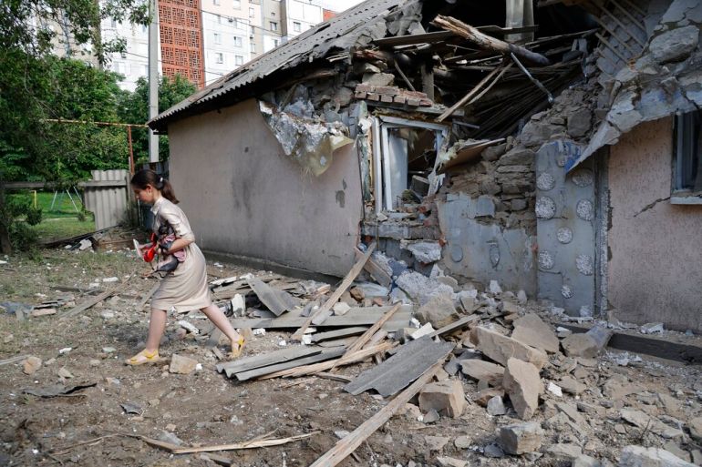 A girl carries a dog past a house damaged from shelling in the Leninsky district of Donetsk, Ukraine.