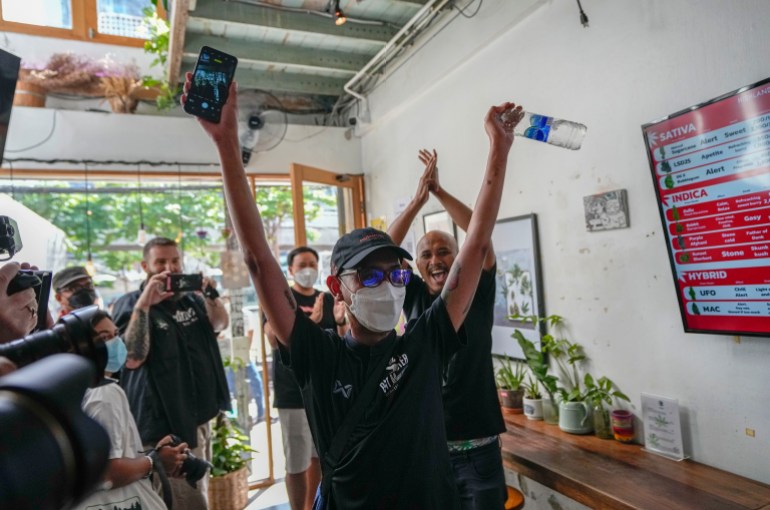 The first customer of the day, Rittipomng Bachkul celebrates after buying legal marijuana at the Highland Cafe in Bangkok, Thailand, Thursday, June 9, 2022. Measures to legalize cannabis became effective Thursday, paving the way for medical and personal use of all parts of cannabis plants, including flowers and seeds. (AP Photo/Sakchai Lalit)