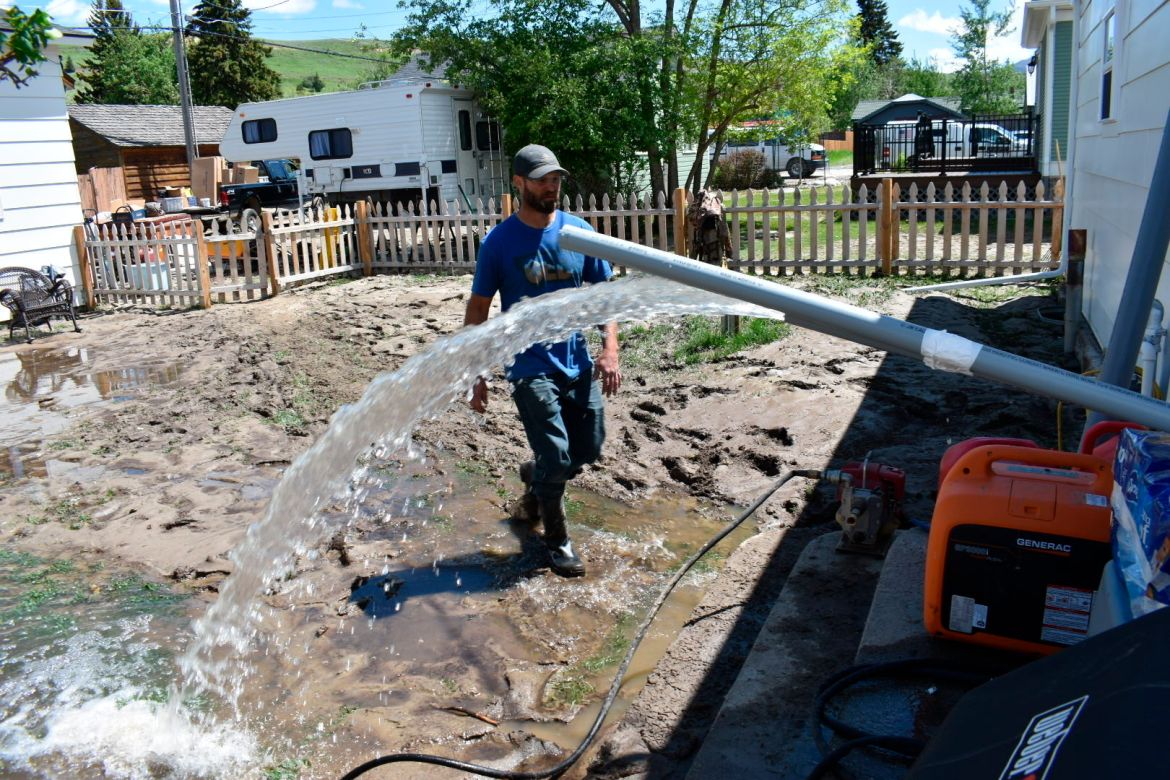 Micah Hoffman is seen in his mud-covered yard as a pump removes water from his basement