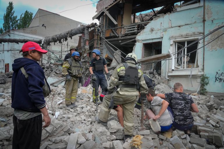 Search and rescue workers and local residents remove a body from under the rubble of a building after a Russian air raid in Lysychansk, Luhansk region, Ukraine, June 16, 2022