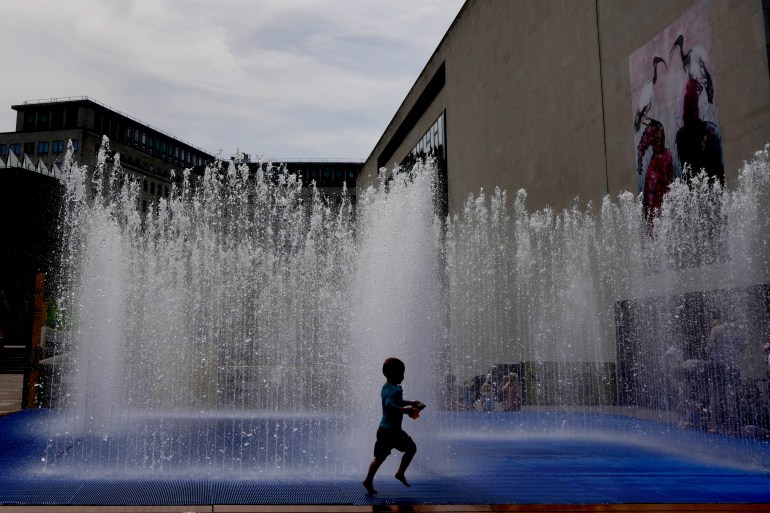 A child plays in a fountain in the warm weather in London, Friday, June 17, 2022.