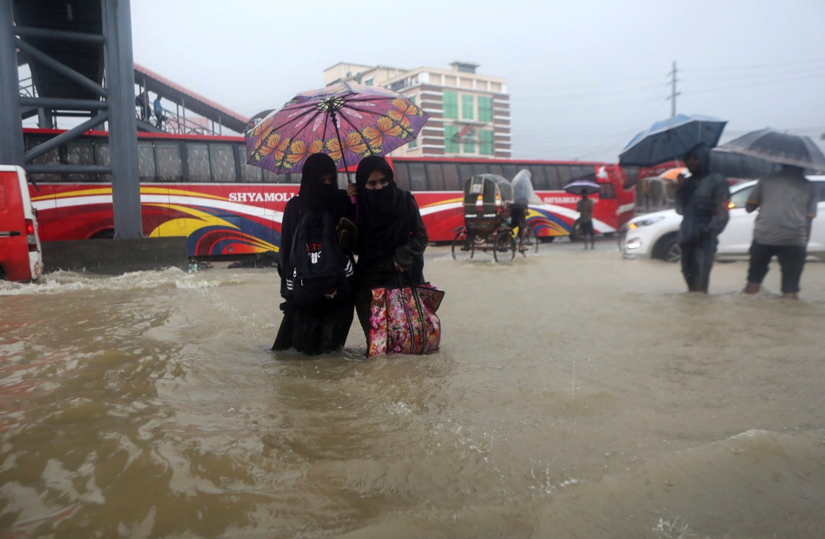 People wade through flooded waters in Sylhet