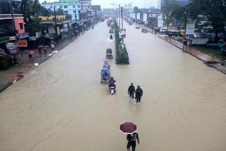 People wade through flooded waters in Sylhet, Bangladesh