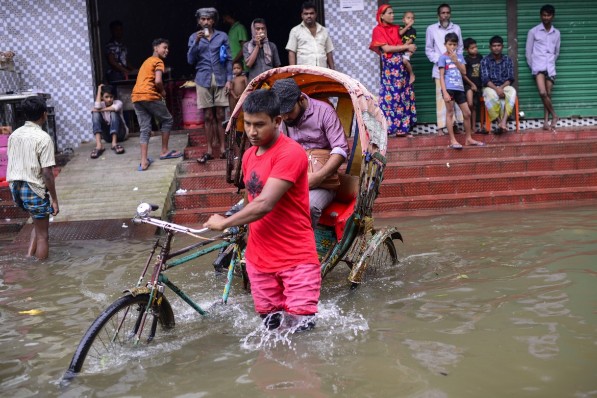 A rickshaw puller wades through flood waters in Sylhet