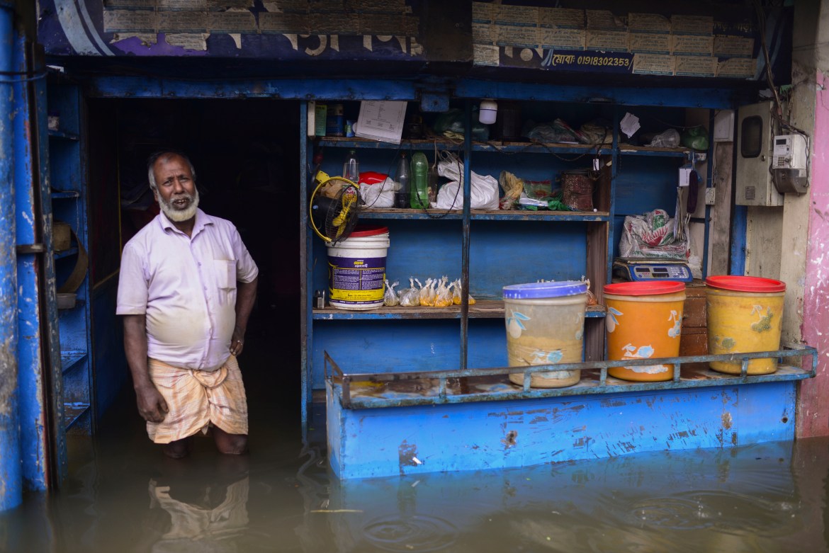 A man stands at the doorway of his flooded shop in Sylhet