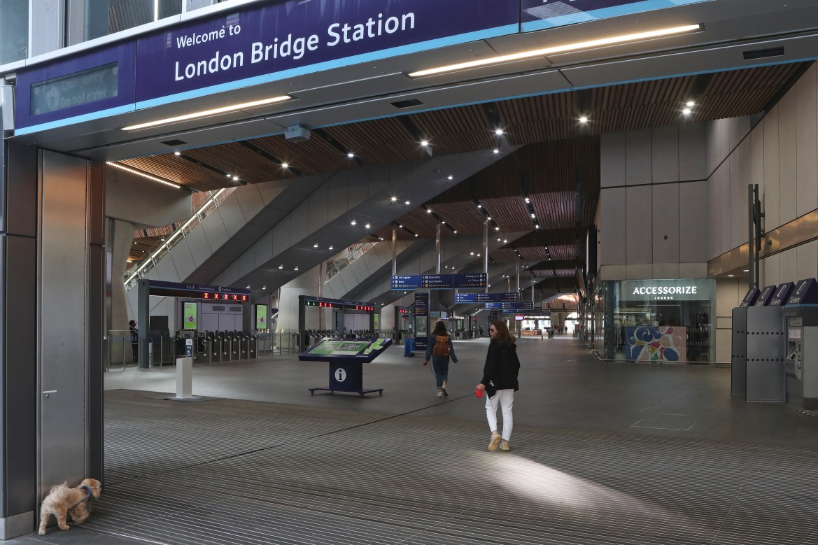 A woman walks her dog into an almost empty London Bridge station