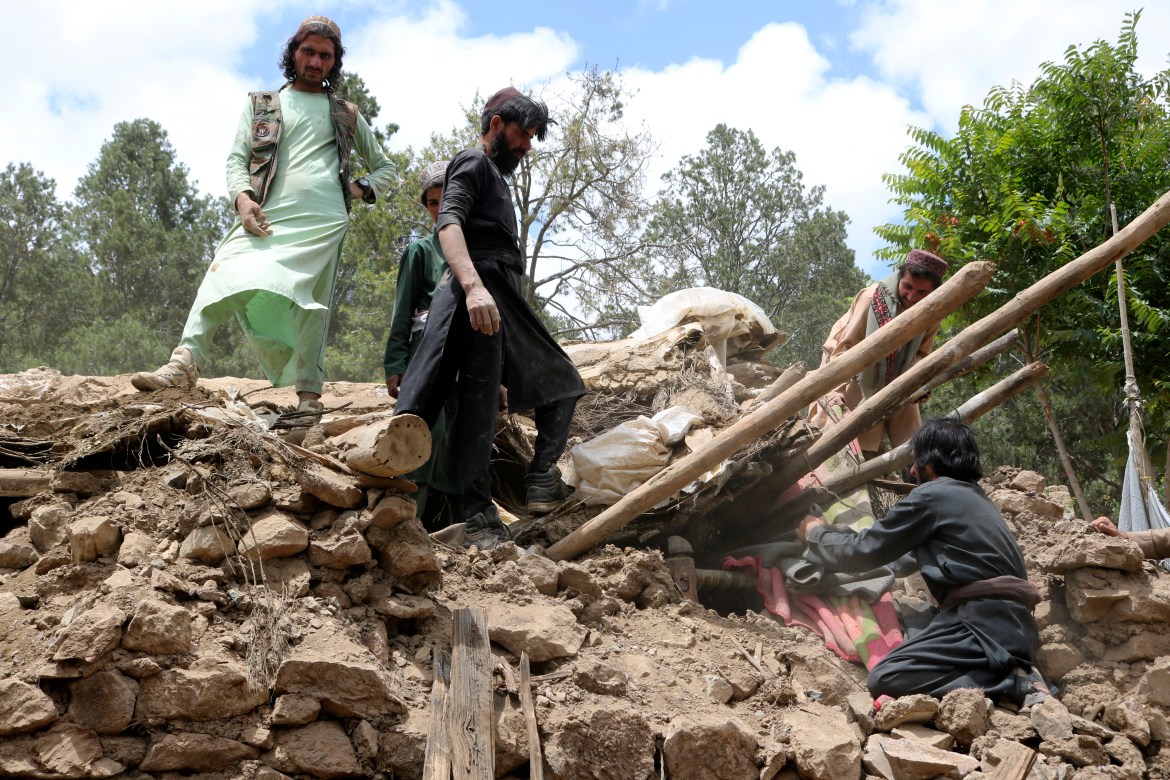 Afghan villagers collects belongings from under the rubble