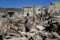 Afghan man carries his child amid destruction after an earthquake in Gayan village.