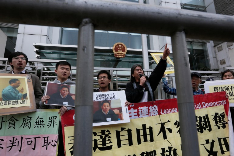 Protesters with photos of legal scholar Xu Zhiyong shout slogans against a Chinese court’s decision to sentence him in prison outside the Chinese liaison office in Hong Kong, Monday, Jan. 27, 2014.