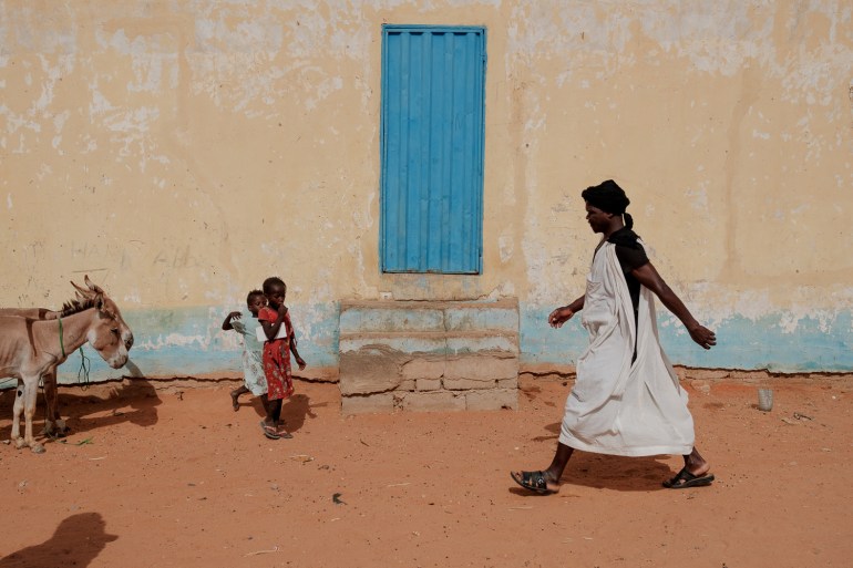 Refugiados do Mali passam por um prédio a caminho do campo semanal de Mbera