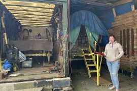 Kathleenanne Boswell with her grandfather&#39;s traditional bow top wagon in storage at Mary Street Caravan Site, Bradford, England [Katharine Quarmby/Al Jazeera]
