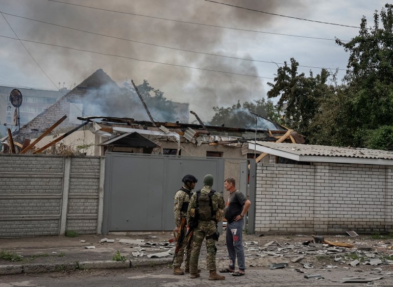 Police officers speak with a local resident as his house burns following shelling, as Russia's attack on Ukraine continues, in Lysychansk, Luhansk region Ukraine June 2, 2022 
