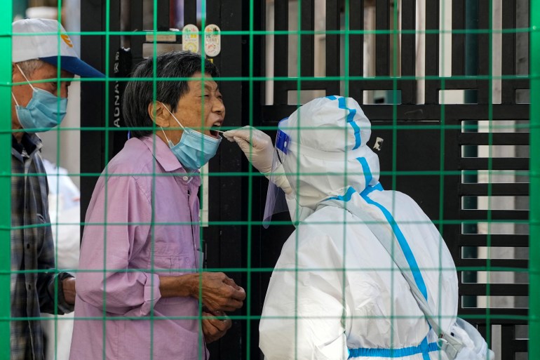 A resident of Shanghai is tested for covid by a health worker in a hazmat suit