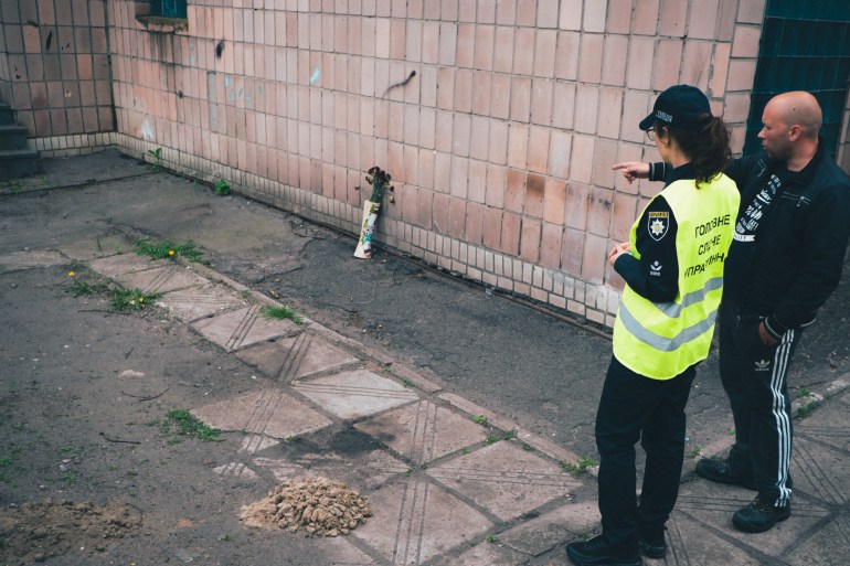 A photo of the police officer Natalya Kozhevnykova speaking to someone who is pointing to an alley.