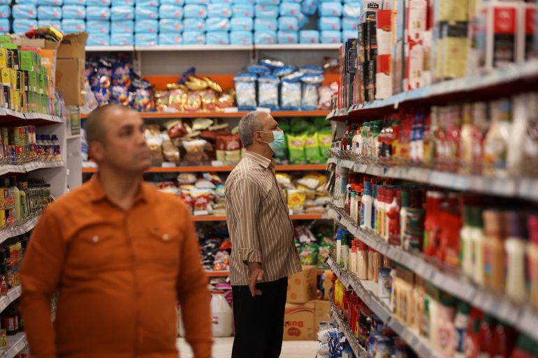 An Iranian man looks at food shelves in a supermarket as the prices of some goods increased in Tehran, Iran