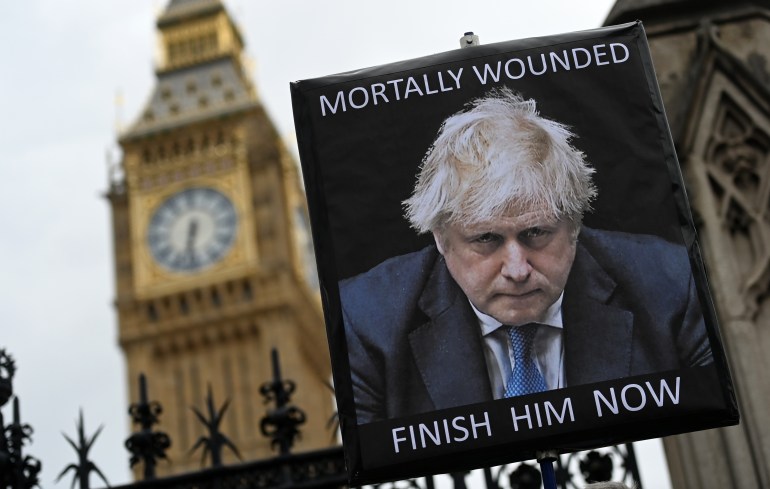 Londra parlamentosu önünde bir protestocu Boris Johnson'a karşı bir pankart tutuyor