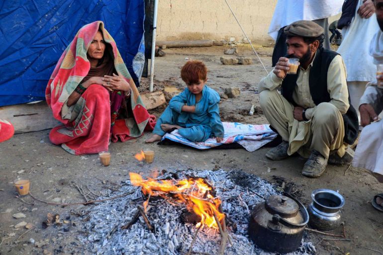Afghans warm themselves round a fire