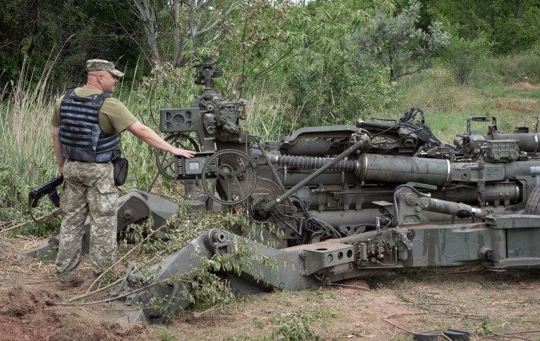 A Ukrainian soldier stands at a US-supplied M777 howitzer in Ukraine's eastern Donetsk region Saturday, June 18, 2022