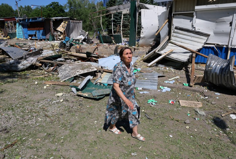 A woman walks past destroyed structures in Donetsk, Ukraine.
