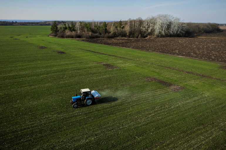 An aerial view shows a tractor spreading fertiliser on a wheat field near the village of Yakovlivka after it was hit by an aerial bombardment outside Kharkiv, as Russia's attack on Ukraine continues