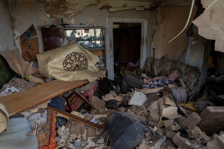 A resident sits on a sofa inside a house damaged after a missile strike in Druzhkivka, eastern Ukraine, Sunday, June 5, 2022