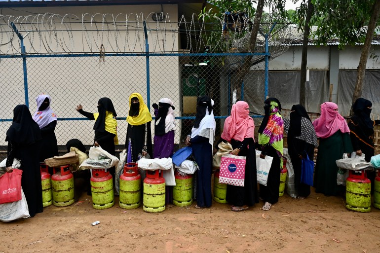 Rohingya women queue for gas canisters against a wire fence topped with barbed wire at the Kutupalong refugee camp in Bangladesh.
