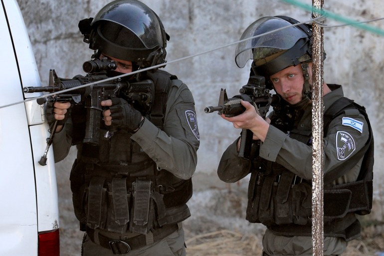 Israeli border guards take aim during a raid on a house in the town of Rummanah, near the flashpoint town of Jenin in the occupied West Bank on May 8, 2022, reportedly the home of Palestinian Subhi Imad Abu Shukair, suspected of carrying out a fatal axe attack in the central city of Elad two days earlier. - Two Palestinians suspected of killing three Israelis in an axe attack in Elad were arrested after a more than two day manhunt, the security services said. (Photo by JAAFAR ASHTIYEH / AFP)