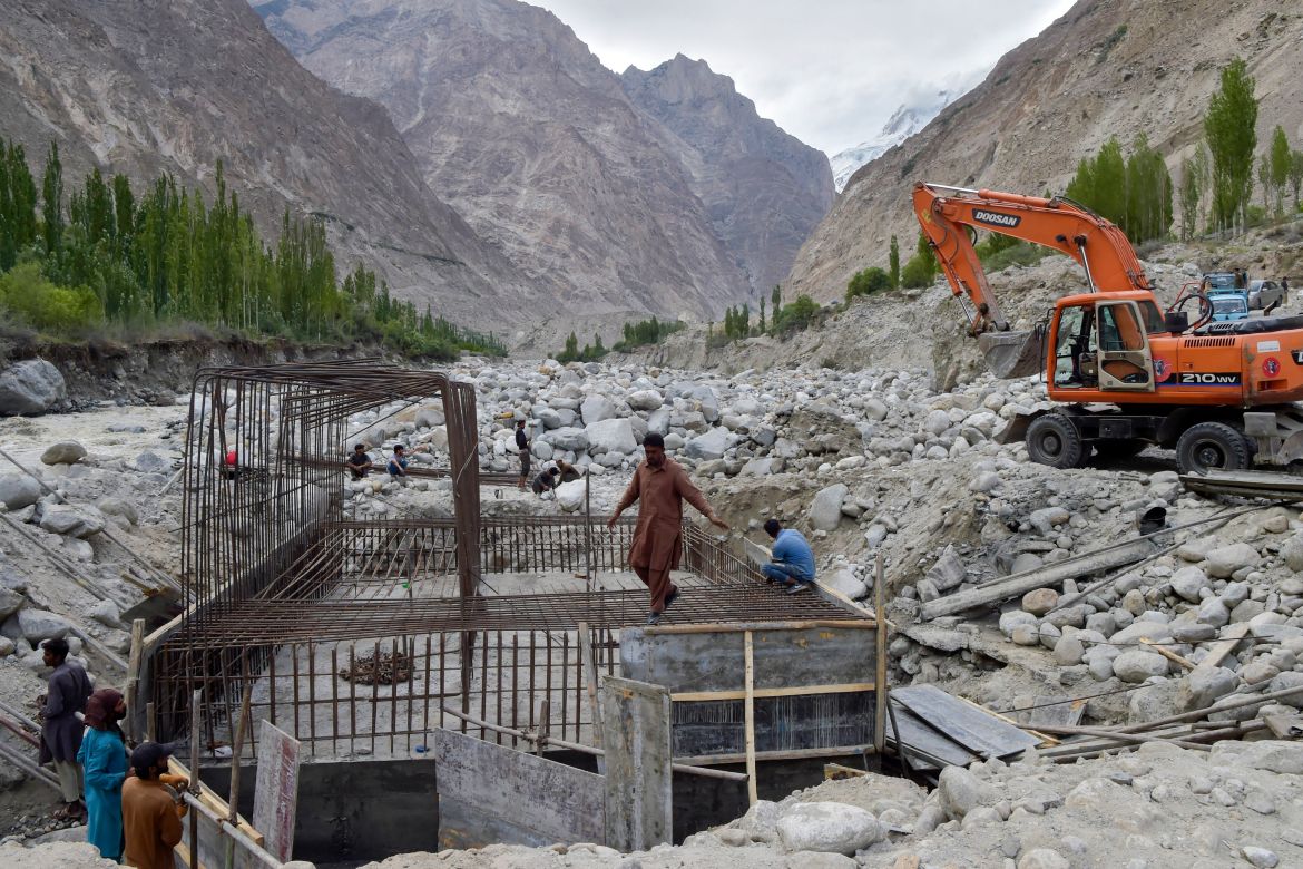 In this picture taken on June 9, 2022, construction workers build a temporary bridge after a lake outburst because of a melting glacier swept away the main bridge in Hassanabad village