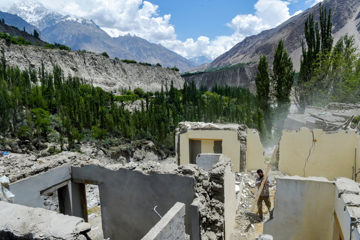 In this picture taken on June 9, 2022, a resident clears debris from a damaged house after a lake outburst because of a melting glacier in Hassanabad village