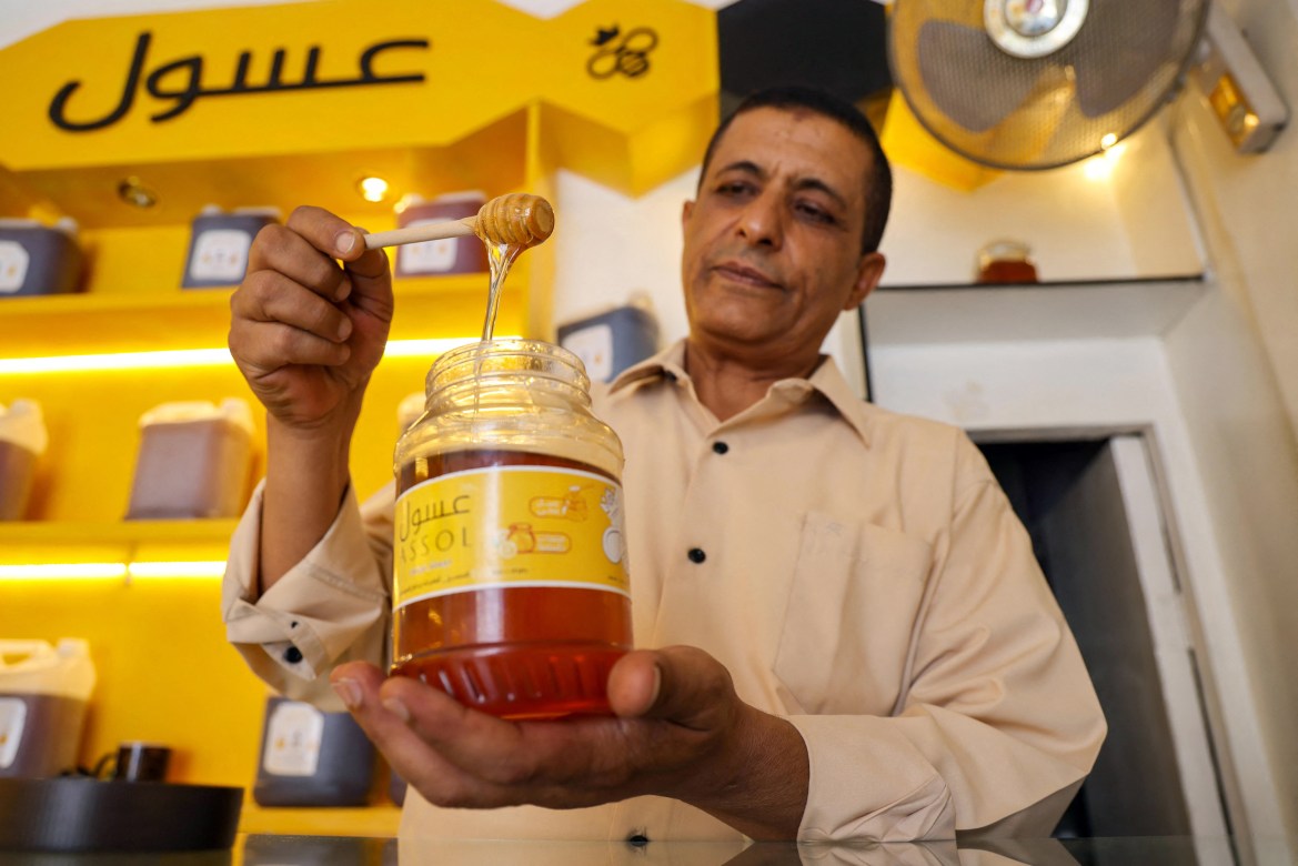 A Yemeni vendor scoops honey from a jar at his shop