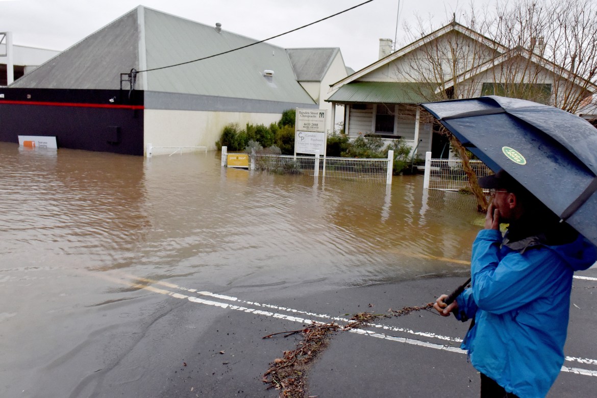 A man looks at a flooded residential area due to torrential rain in the Camden suburb