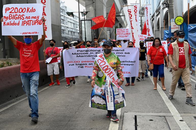 A woman wearing a dress made of rice sacks walks in a protest calling on the Philippines president to lower rice prices