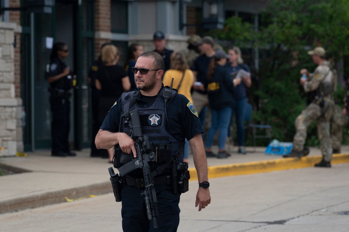 A police officer searches the scene of the Fourth of July parade shootin