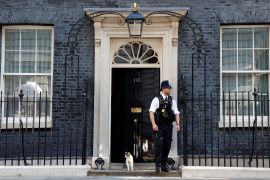 Larry, the Downing Street cat, sits on the step next to a police officer outside 10 Downing Street in London, UK.