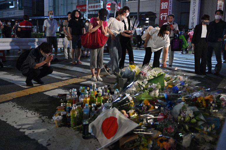 People pay their respects in front of a makeshift memorial outside Yamato-Saidaiji Station, where former Japanese prime minister Shinzo Abe was shot earlier in the day, in Nara on July 8, 2022. - Abe was pronounced dead on July 8, the hospital treating him confirmed, after he was shot at a campaign event in the city of Nara. (Photo by Philip FONG / AFP)