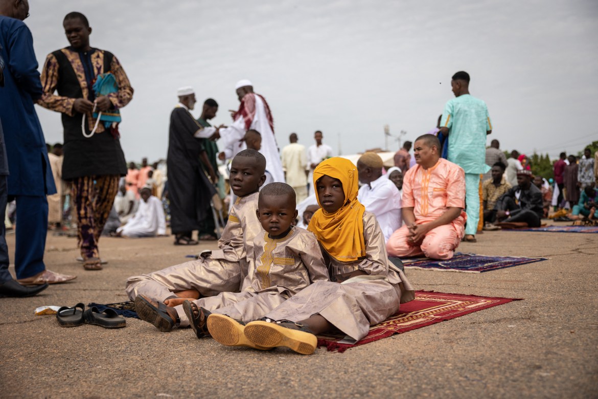 Muslim children sit on a prayer mat after the great prayer on the first day of the Eid al-Adha