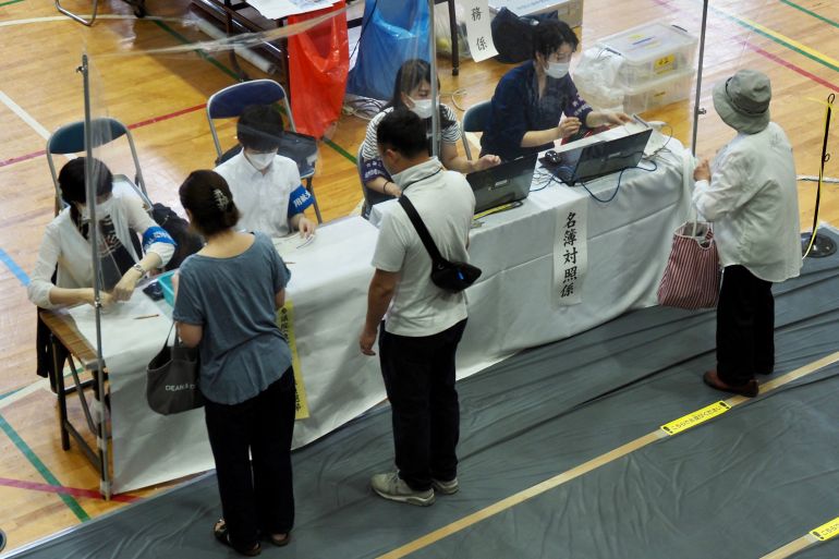 Voters receive their ballots during Japan's upper house elections at a polling station in Tokyo on July 10, 2022
