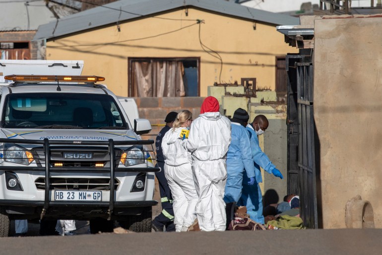 Members of the South African Police Service (SAPS) and forensic pathology service inspect the scene of a mass shooting in Soweto, South Africa,